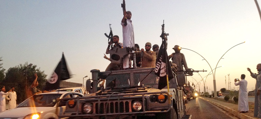 Fighters from the Islamic State group parade in a commandeered Iraqi security forces armored vehicle down a main road at the northern city of Mosul, Iraq.