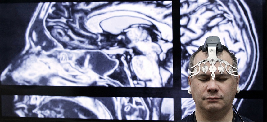 BrainScope employee Doug Oberly wears a brain scanning headset at the NFL owners' meeting in Boca Raton, Fla.