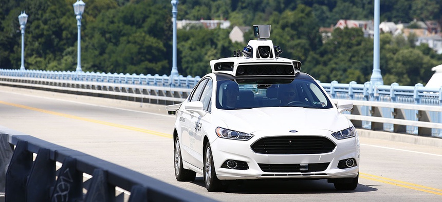 Uber employees test a self-driving Ford Fusion hybrid car, in Pittsburgh.