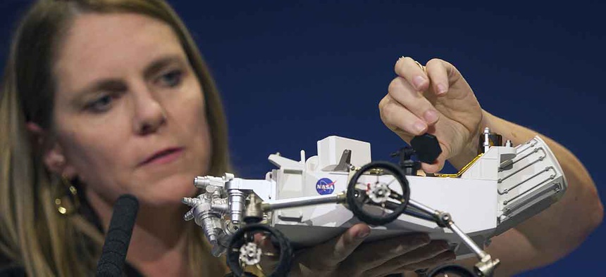 Jennifer Trosper, Mars Science Laboratory, MSL mission manager, JPL, adjusts the high-gain antenna on a rover model during a news briefing on the last data and imagery from Sol 1 at NASA's Jet Propulsion Laboratory.