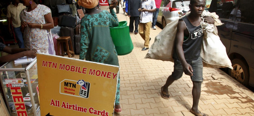 Pedestrians walk past a mobile money point in Kampala, Uganda.