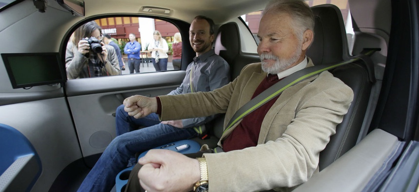 Steve Mahan, who is blind, gestures for a steering wheel that doesn't exist inside a Waymo driverless car during a Google event, Tuesday, Dec. 13, 2016, in San Francisco.