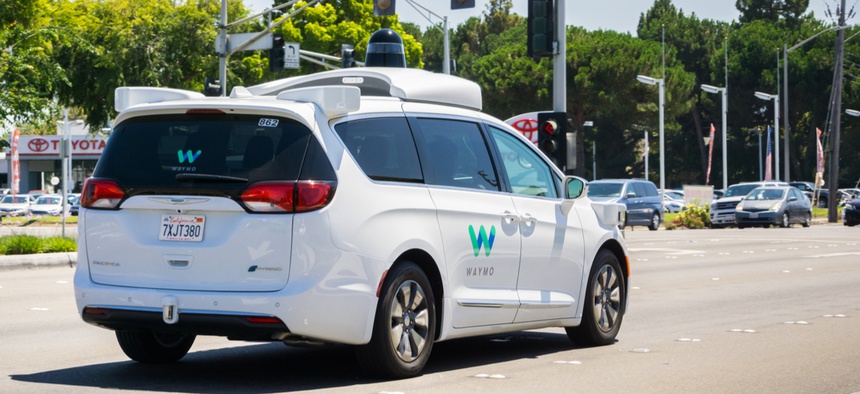 Waymo self-driving car cruising on a street in August.