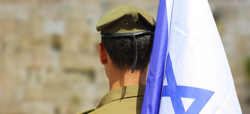Israeli soldier with flag of Israel on blurred background of Western Wall.