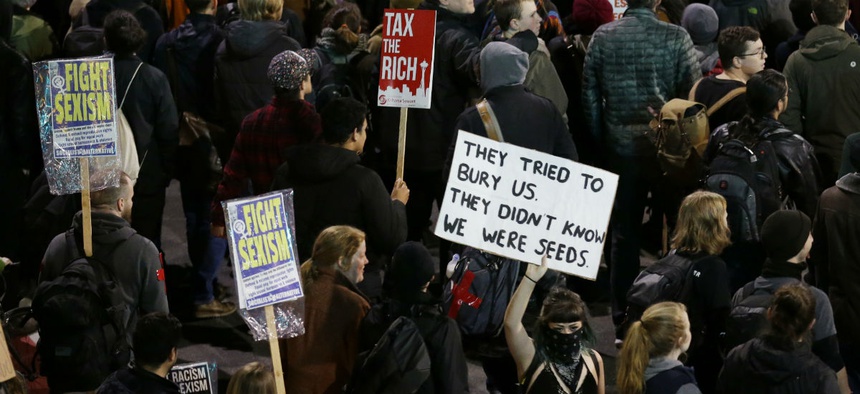Protesters hold signs during a protest march against President Donald Trump, Friday, Jan. 20, 2017, in Seattle.