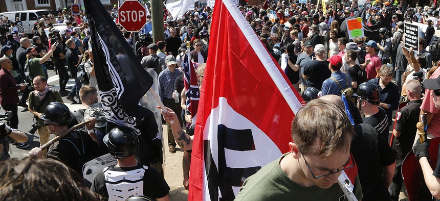 A white supremacist carries a Nazi flag into the entrance to Emancipation Park in Charlottesville, Va.