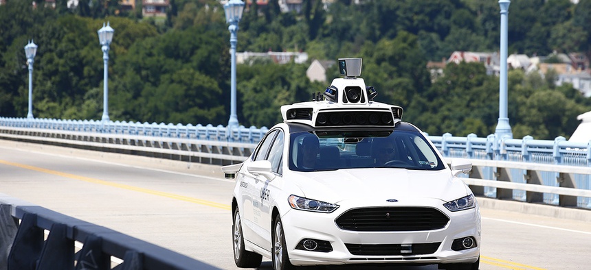 Uber employees test a self-driving Ford Fusion hybrid car, in Pittsburgh.