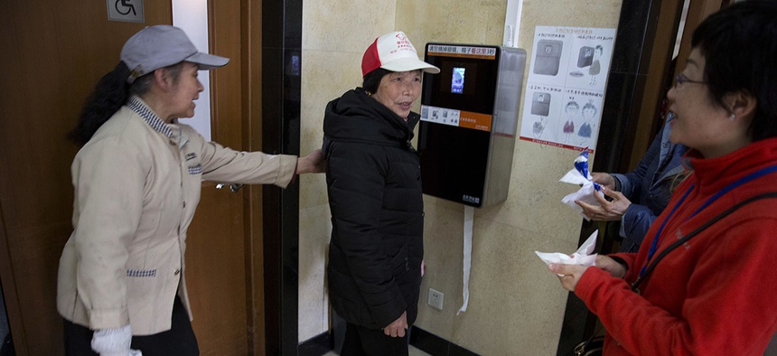March 21, 2017, visitors to the toilet at the Temple of Heaven park try out a facial recognition toilet paper dispenser in Beijing, China.