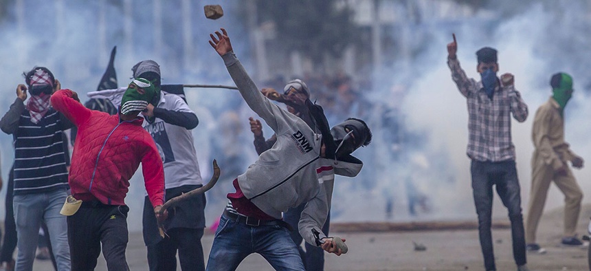 Masked Kashmiri protesters throw rocks at government forces during a protest outside Eidgha, a prayer ground, in Srinagar, Indian controlled Kashmir, Saturday, Sept. 2, 2017.