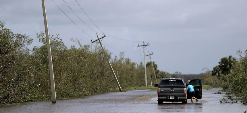 A motorist stands in water on a flooded road from Hurricane Irma leading to Marco Island, Fla., Monday, Sept. 11, 2017.
