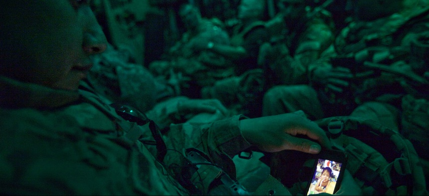 Staff Sgt. Rulberto Qjendismiranda, 20, of Seaside, Calif, with the U.S. Army's 2nd Battalion 27th Infantry Regiment based in Hawaii, looks at a photo of his son Marziano, 11 months, on his mobile phone aboard a military transport flight.
