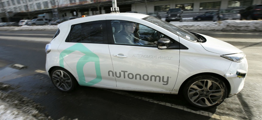 An autonomous vehicle is driven by an engineer on a street through an industrial park, in Boston.