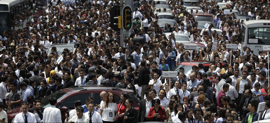 People evacuated from office buildings gather in Reforma Avenue after an earthquake in Mexico City, Tuesday Sept. 19, 2017.