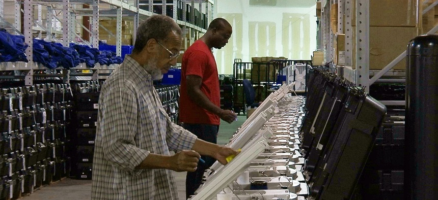 This Sept. 22, 2016 photo shows employees of the Fulton County Election Preparation Center in Atlanta test electronic voting machines.