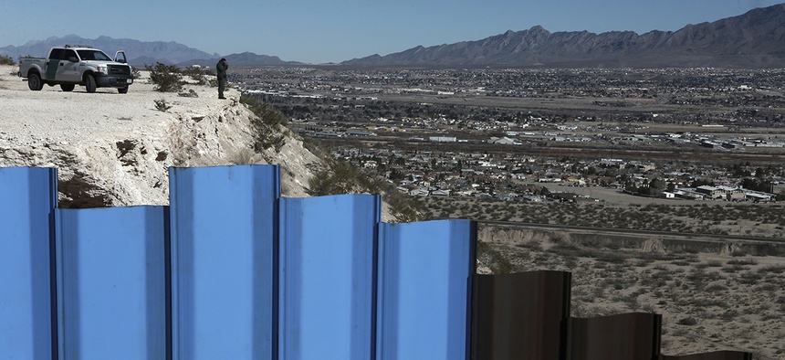 An agent of the border patrol, observes near the Mexico-US border fence, on the Mexican side.