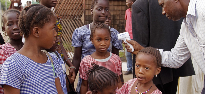A health care worker, right, takes the temperatures of school children for signs of the Ebola virus before they enter their school in the city of Conakry, Guinea, Monday, Jan. 19, 2015.