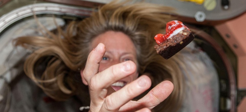 NASA astronaut Karen Nyberg floats a piece of food during mealtime. NASA astronaut Karen Nyberg floats a piece of food during mealtime.