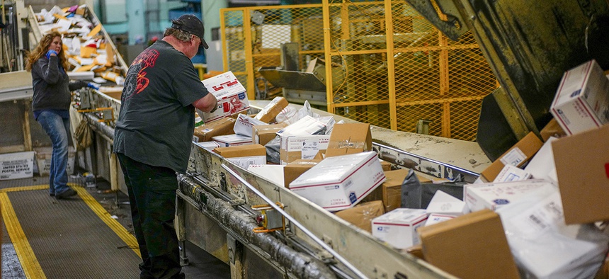 Steve Robino arranges packages on a conveyor belt at the main post office in Omaha, Neb., Thursday, Dec. 14, 2017.