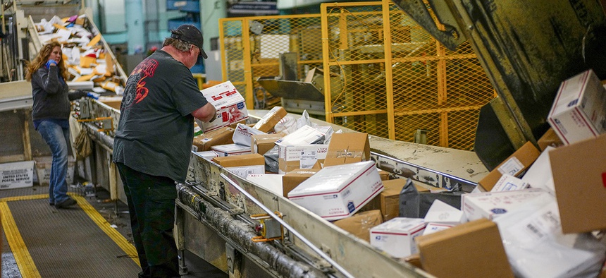 Steve Robino arranges packages on a conveyor belt at the main post office in Omaha, Neb., Thursday, Dec. 14, 2017.