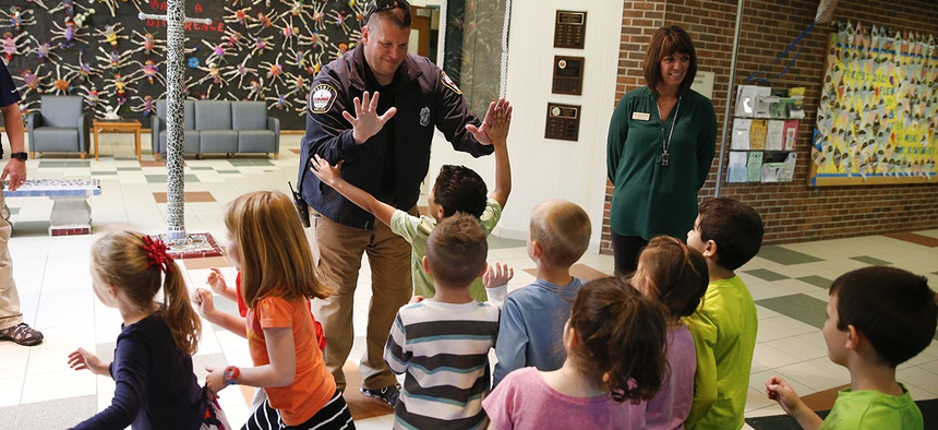 Forest Dale Elementary School principal Deanna Pitman, right, and Carmel, (Ind.) police officer Greg DeWald welcome students as they return to the school following an intruder drill at the school in Carmel, Ind.