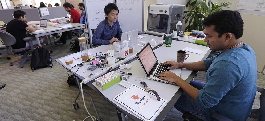 Babson College graduate school alumnus and Visa applicant Abhinav Sureka, of Mumbai, India, right, types in his work space at the college in Wellesley, Mass.
