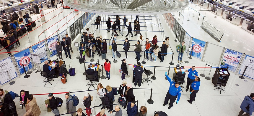Passengers stand in line as they wait to pass through a TSA security checkpoint at JFK International Airport in New York.