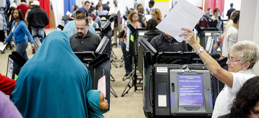 A child watches as a polling worker waves over an early voter to an open booth at the Franklin County Board of Elections, Monday, Nov. 7, 2016, in Columbus, Ohio.