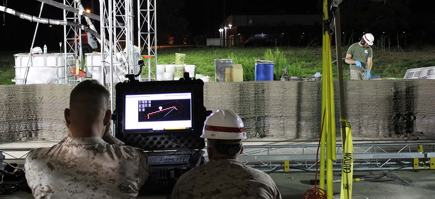 Marines from I Marine Expeditionary Force monitor the computer while the world's largest concrete 3D printer constructs a 500-square-foot barracks hut at the U.S. Army Engineer Research and Development Center in Champaign, Illinois.