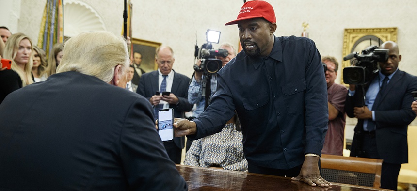 Rapper Kanye West shows President Donald Trump a photograph of a hydrogen plane during a meeting in the Oval Office of the White House, Thursday, Oct. 11, 2018, in Washington.