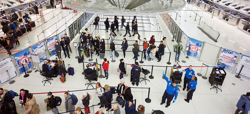 Passengers stand in line as they wait to pass through a TSA security checkpoint at JFK International Airport in New York.