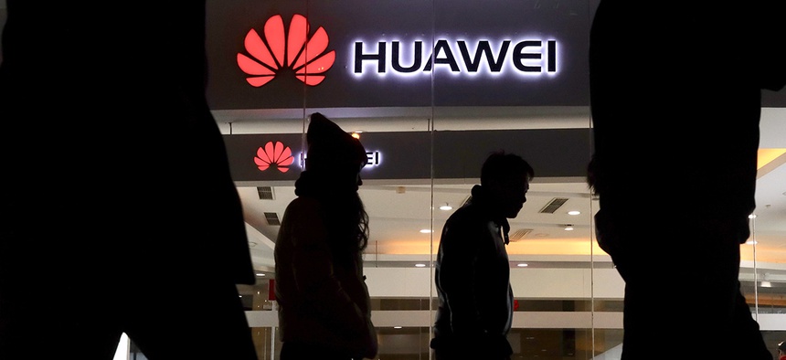 Pedestrians walk past a Huawei retail shop in Beijing Thursday, Dec. 6, 2018.