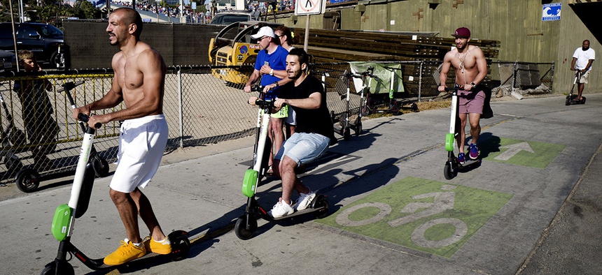 People ride Lime and Bird scooters along the strand in Santa Monica, Calif.