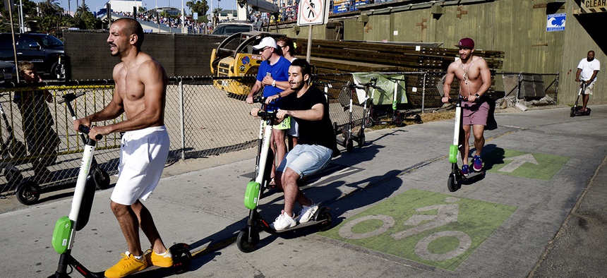People ride Lime and Bird scooters along the strand in Santa Monica, Calif.