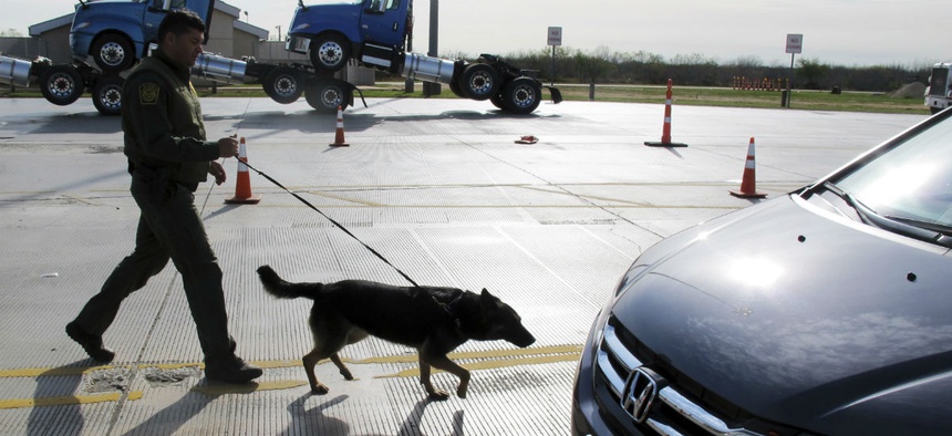 A Border Patrol agent uses a dog to inspect vehicles lining up at the Laredo North vehicle checkpoint in Laredo, Texas, Feb. 2.