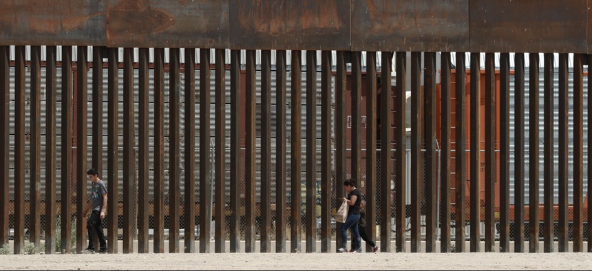 Three migrants who had managed to evade the Mexican National Guard and cross the Rio Grande onto U.S. territory walk along a border wall set back from the geographical border, in El Paso, Texas, as seen from Ciudad Juarez, Mexico, in July.