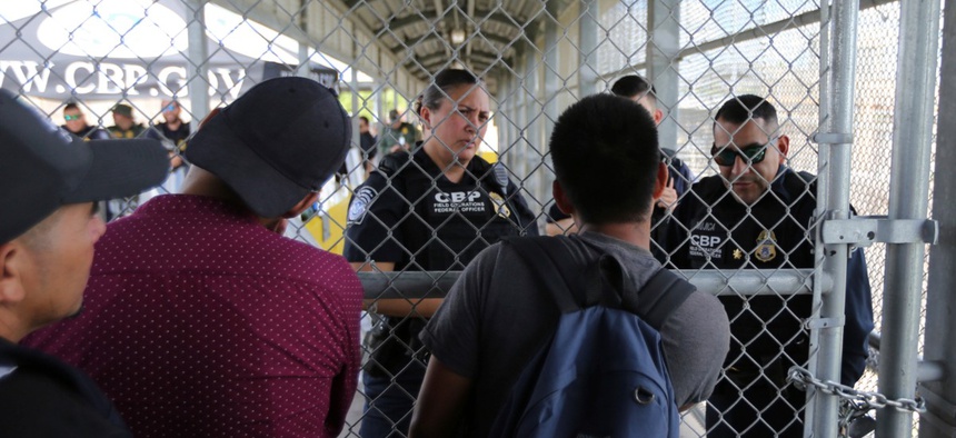 Migrants ask Customs and Border Protection officers when will the border re-open, after camping out on the Gateway International Bridge that connects downtown Matamoros, Mexico with Brownsville Oct. 10.