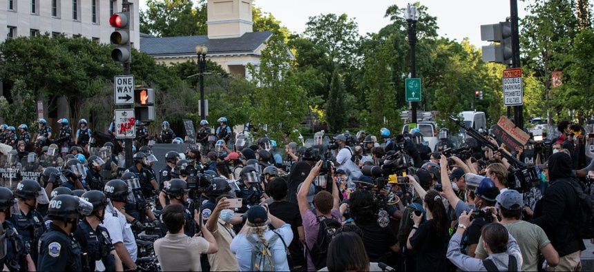 Washington Metropolitan Police officers, U.S. Park Police mounted officers, the District of Columbia National Guard Military Police and Department of Homeland Security officers watch as demonstrators near the White House June 1.