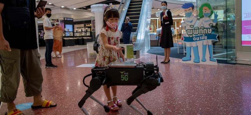 A child disinfects her hands from a mobile robot that carries a container of sanitization liquid at Central World, an upmarket shopping mall in Bangkok, Thailand, Wednesday, May 27, 2020.