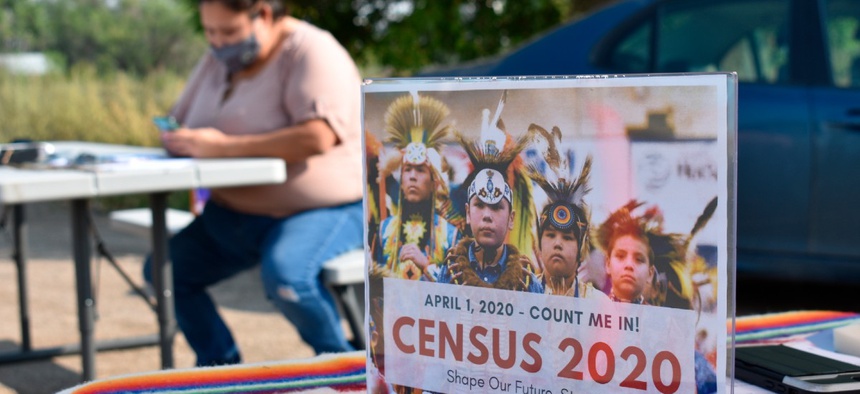 A sign promoting Native American participation in the U.S. census is displayed as Selena Rides Horse enters information into her phone on behalf of a member of the Crow Indian Tribe in Lodge Grass, Mont. on Wednesday, Aug. 26, 2020.