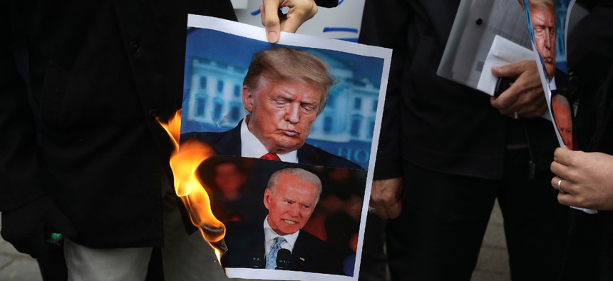 Protesters burn pictures of the U.S. President Donald Trump, top, and the President-elect Joe Biden in a gathering in front of Iranian Foreign Ministry on Nov. 28, a day after the killing of Iranian scientist Mohsen Fakhrizadeh.